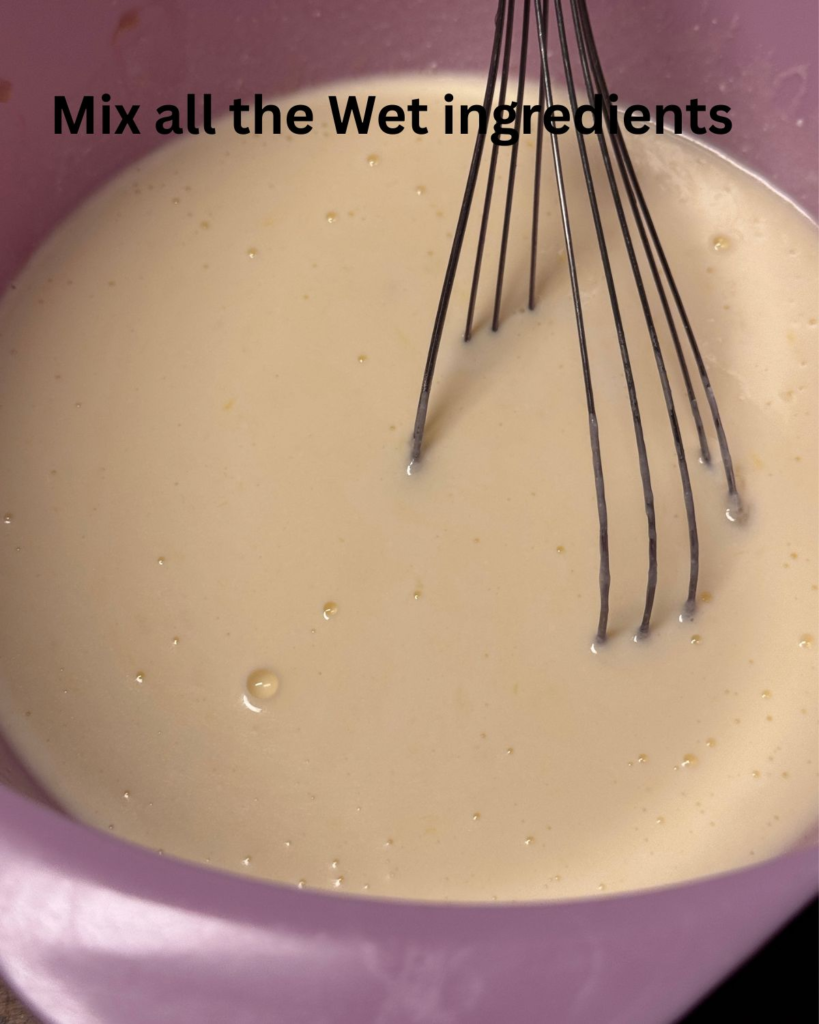 Whisking wet ingredients for easy buttermilk pancakes in a pink mixing bowl until smooth.