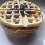 Stack of homemade blueberry waffles from scratch topped with fresh blueberries