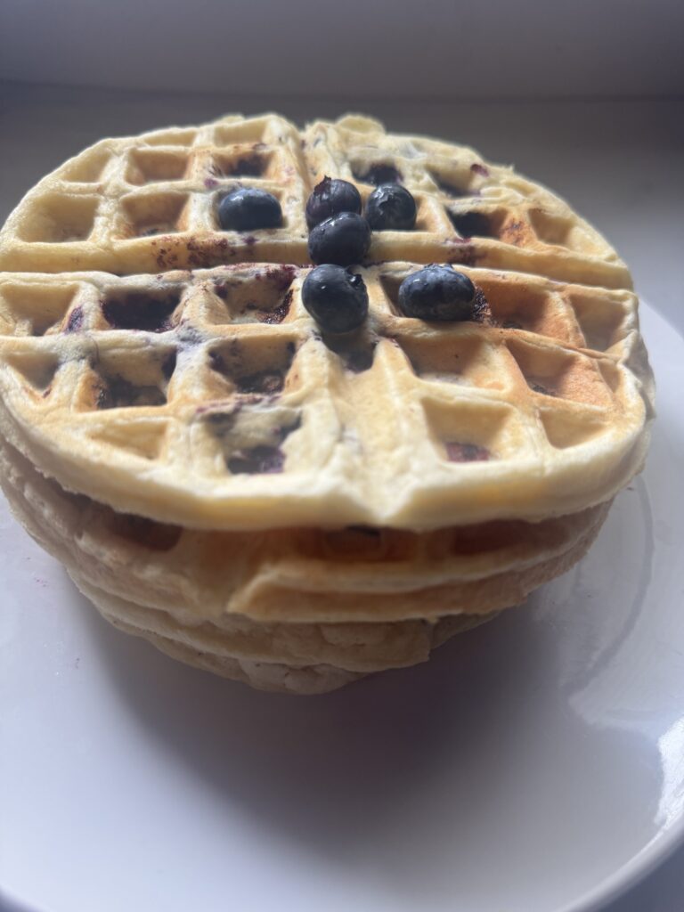 Stack of homemade blueberry waffles from scratch topped with fresh blueberries