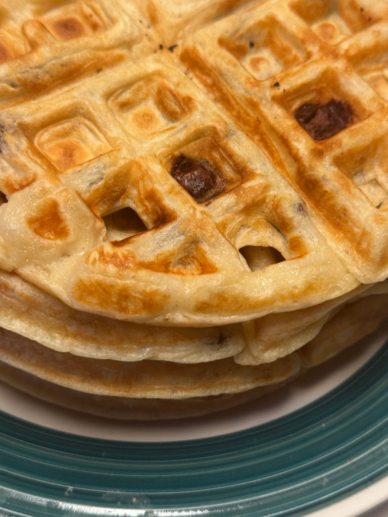 Easy chocolate chip waffles from scratch stacked on a plate, golden brown and fluffy with melted chocolate chips