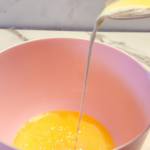 Pouring milk and melted butter into a bowl to make a homemade heavy cream substitute.