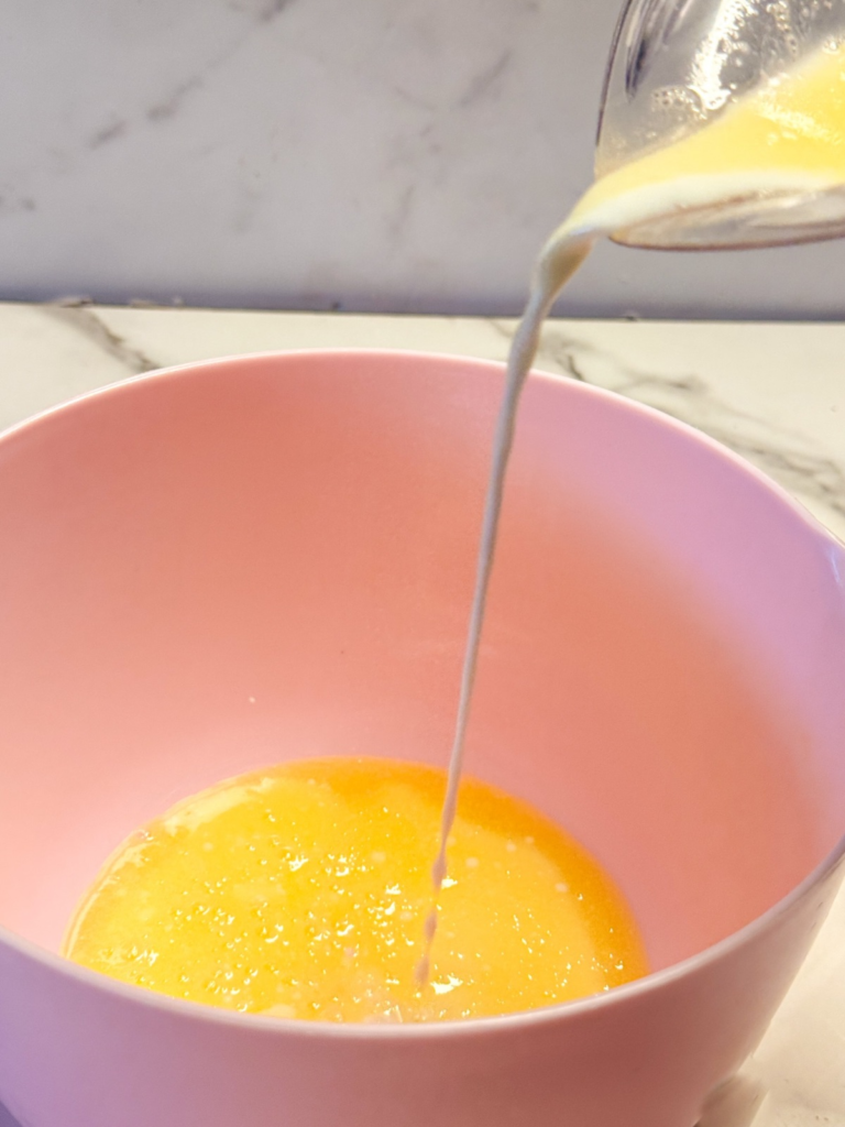 Pouring milk and melted butter into a bowl to make a homemade heavy cream substitute.