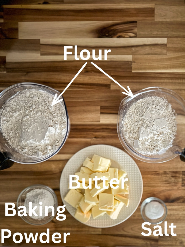 Ingredients for homemade Bisquick mix including flour, butter, baking powder, and salt arranged on a wooden countertop.