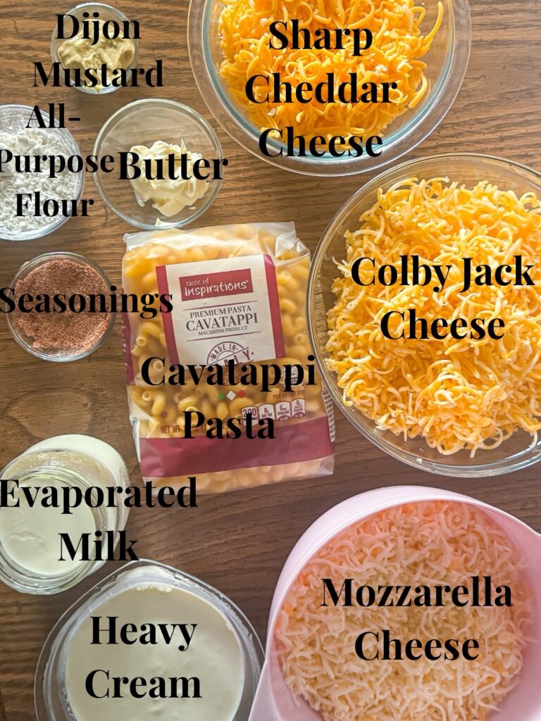Ingredients for homemade mac and cheese including cavatappi pasta, sharp cheddar, colby jack, mozzarella cheese, evaporated milk, heavy cream, butter, flour, Dijon mustard, and seasonings