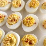 Classic deviled eggs topped with paprika on a serving tray