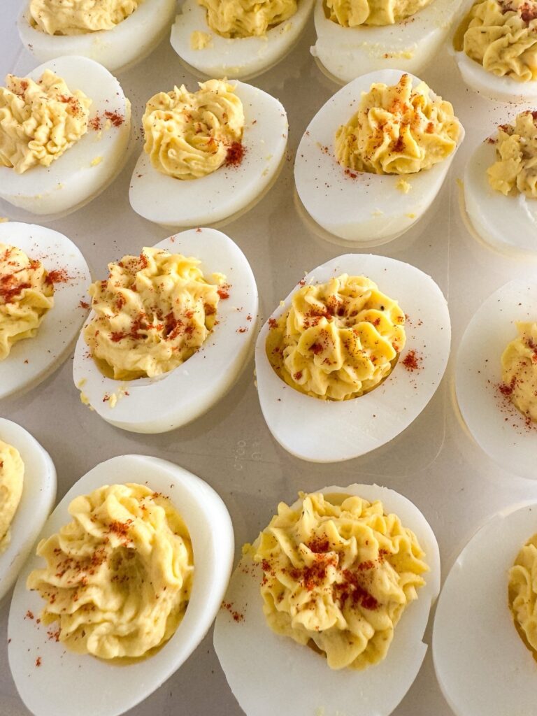 Classic deviled eggs topped with paprika on a serving tray