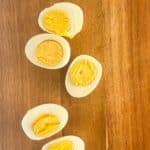 Perfect hard boiled eggs cut in half showing fully cooked yellow yolks and firm whites