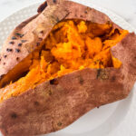 Baked sweet potato with soft fluffy inside on a white plate