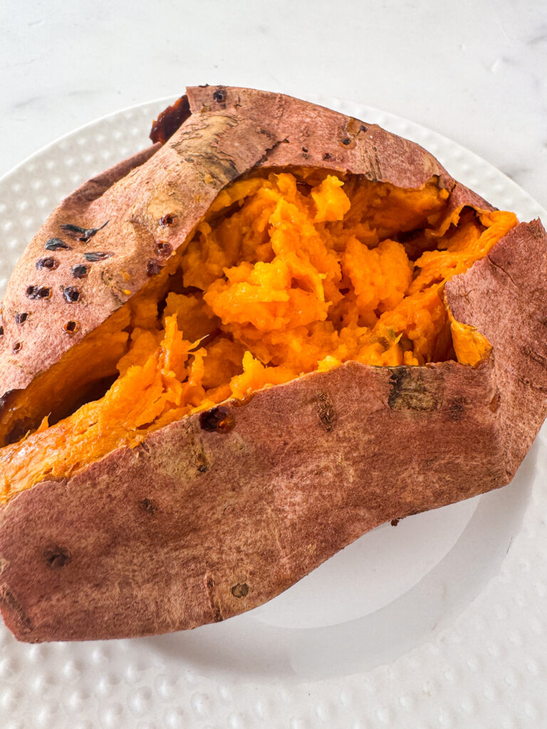 Baked sweet potato with soft fluffy inside on a white plate